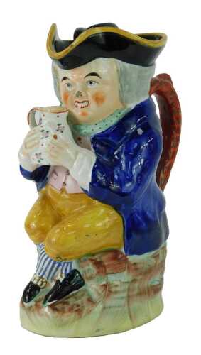 A 19thC pottery Toby jug, modelled as a seated gentleman wearing a tricorn hat with lid, grasping a tankard of beer, 25cm high.