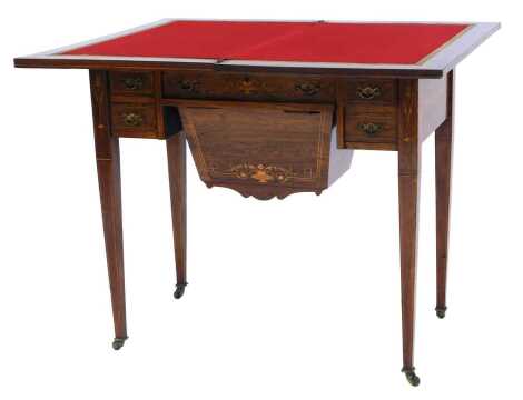 An Edwardian walnut and marquetry games table, the hinged top enclosing a red felted interior, the base with drawer enclosing an arrangement of recesses, above a deep drawer flanked by two small drawers to each side, on square tapering legs, on castors, 7