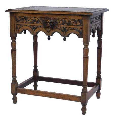 An early 20thC side table, the rectangular carved top above a floral carved drawer with animal mask handle, on turned legs with stretchers, 73cm high, 66cm wide, 44cm deep. (AF)