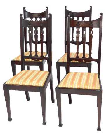 A set of four walnut Art Nouveau dining chairs, each with a pierced back with carved Art Nouveau floral motifs, overstuffed seat, on square tapering legs with spade feet.