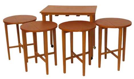 A mid century teak nest of tables, the largest with a rectangular top, raised on cylindrical tapering legs, on castors, 57cm high, 62cm wide, 42cm deep, with four integrated drop leaf tables within.