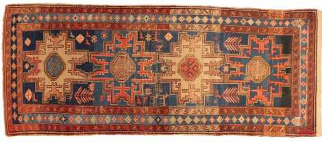 A Kazak rug, blue ground, with multiple medallion decoration, within three narrow borders, 108cm x 264cm. (AF)