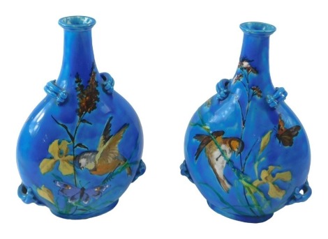 A pair of Clément Massier pottery vases, each decorated with birds seated on branches, butterflies, etc., in raised coloured slip, oval paper label to underside, numbered 485, 28cm high. (AF)