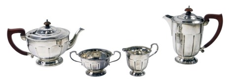 An Edward VII/George VI silver four piece tea set, comprising teapot, coffee pot, milk jug, sugar bowl, with fluted border and brown ebonised handle and knop, Birmingham 1936 and 1937, 35.05ozt gross.