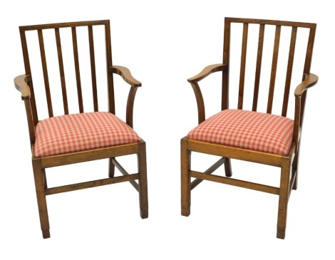 A pair of 20thC Cotswold School type elbow chairs, after a design by Edward Barnsley, each with a slatted back and a gingham patterned padded seat, stamped to underside Glenister Maker Wycombe, and with the cipher for George VI, from a North Yorkshire RAF