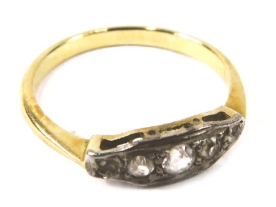 An Art Deco dress ring, the panel set with five old cut diamonds, each in a white gold setting in a raised basket, on a plain yellow metal band, unmarked, ring size N½, 2.3g all in.