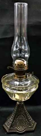 A late Victorian/early 20thC cast iron and clear glass oil lamp, with chimney, 54cm high overall.