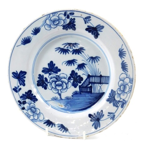 A late 18th/early 19thC Delft plate, decorated in blue with Chinese style flowers, a fence, etc., 24cm diameter.