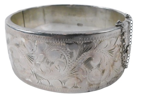 An mid 20thC silver hinged bangle, the half hinged floral design, with clip and safety chain, maker RPH, Birmingham 1964, 43.1g.