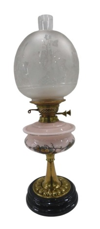 A 19thC brass oil lamp, the etched ivy and floral shade, on a pink glass reservoir decorated with fruits and flowers, on an ebonised and brass stem, 61cm high.