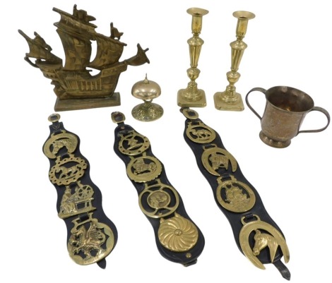 A pair of brass candlesticks, horse brasses, desk bell, silver plated two handled loving cup, ship masted door stop, etc.