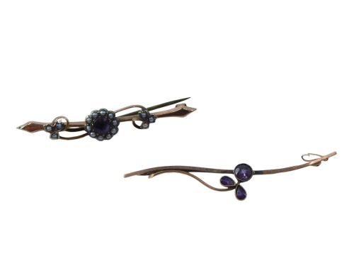 Two bar brooches, comprising an amethyst and seed pearl floral cluster bar brooch, yellow metal unmarked, and an amethyst grape vine type swirl brooch, yellow metal, unmarked, 5cm and 6cm long, 4.2g all in.