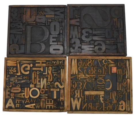 A collection of four square printers trays, each inset with various printers numbers, letters, etc., 40cm and 42cm wide respectively.