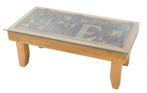 A pine coffee table, the rectangular top inset with various printer's letters in various different type faces, covered with a rectangular piece of glass, 93cm wide.