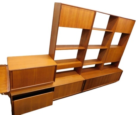 A mid century G Plan teak wall unit, comprising two sections with shelves, pairs of doors, sliding doors, a fall front door, and a separate unit with sliding doors, 306cm wide.