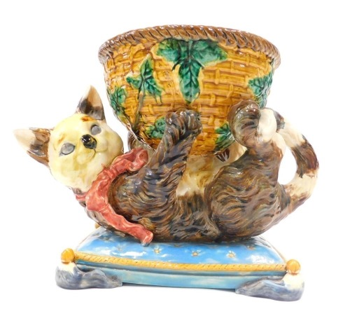 A Majolica centrepiece or jardiniere, modelled in the form of cat holding a basket, seated on a turquoise coloured cushion with gold piping, bearing Minton name to underside, 27cm high, 35cm wide.