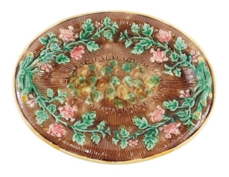 A 19thC Majolica oval serving plate, on a brown bark ground decorated with vines and berries, 29cm x 35cm.