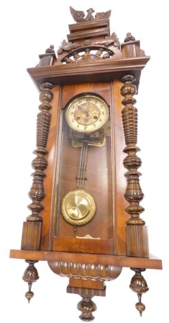 A late 19th/early 20thC Vienna wall clock, the crest decorated with an eagle, the paper dial with Arabic numbers, flanked by turned pilasters, 100cm high overall.