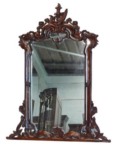 A carved hardwood overmantel mirror, decorated with scrolls, etc., 126cm high, 93cm wide.