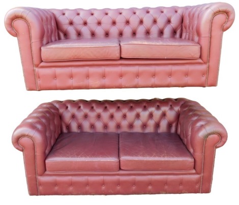 A pair of red oxblood leather Chesterfield sofas, each with a button back, two cushions, and metal studded borders, 187cm wide. The upholstery in this lot does not comply with the 1988 (Fire & Fire Furnishing) Regulations, unless sold to a known exporter 