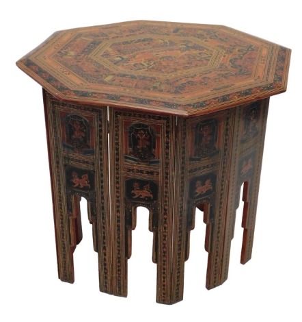 An Oriental occasional table, the octagonal top elaborately painted in red, blue, etc., with figures within interiors, and trees, etc., with folding base, the top 76cm wide, 69cm high including top.