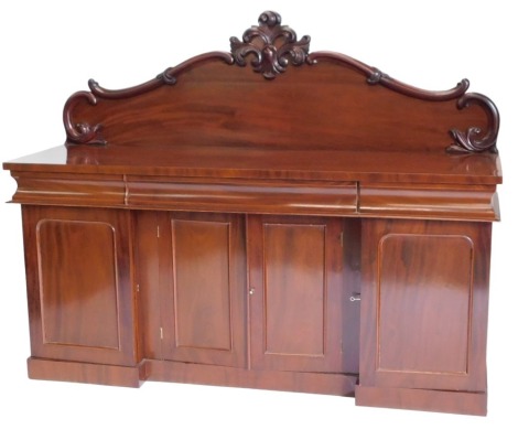 A Victorian mahogany sideboard, the raised back decorated with scrolls, the base with three frieze drawers, above four panelled doors, on inverted breakfront plinth, 130cm high, 181cm wide.