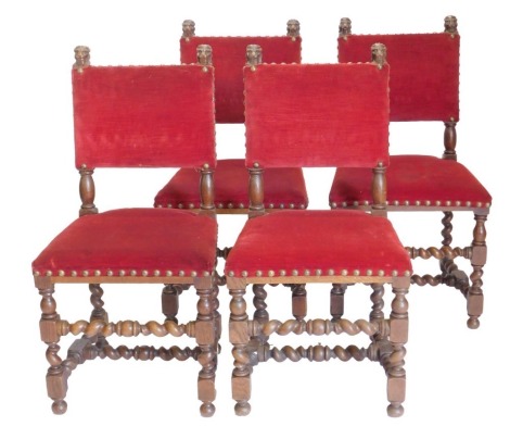 A set of four oak dining chairs, each with a red velvet padded back, on spirally turned supports with stretcher, the boarders with large brass studs.