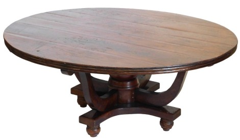 An Old Java colonial style hardwood dining table, with circular top, on four outswept supports, on a concave plinth and bun feet, 176cm diameter.