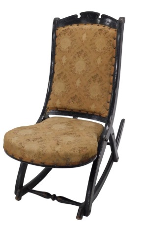 A Victorian folding ebonised rocking chair, with a padded back and seat.