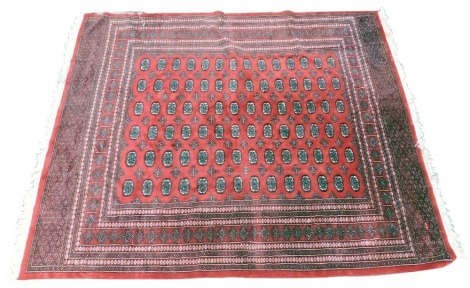 A Pakistani hand knotted carpet, with an all over design of medallions and lozenges, on a red ground, one wide and five narrow borders, 364cm x 247cm.