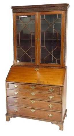 A 19thC mahogany bureau bookcase, the top with a dentil cornice, above a blind frieze, with two astragal glazed doors flanked by canted blind fret sides, the base with a fall enclosing fitted interior, above four graduated drawers with brass drop handles,