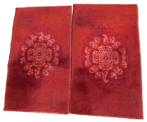 A pair of Oriental carpets, each with a design of scrolls, on a deep red ground, 134cm x 75cm. (AF)