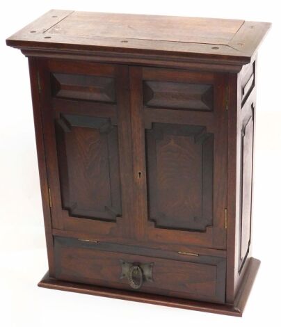 An early 20thC oak Arts & Crafts smoker's cabinet, with panelled sides and doors, enclosing a single shelf, above a hinged compartment with hammered pewter handle, 41cm wide.