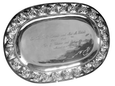 A presentation oval salver, with petalated rose embossed border, and central inscription dated 1976, white metal stamped Mexico 925, 12.32oz, 30cm wide.