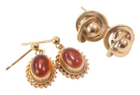 Two pairs of earrings, comprising an orange agate set 9ct gold pair of studs, with rope twist border, lacking butterfly backs, and a pair of unmarked yellow metal twist studs, on single backs with butterfly backs, 2.3g all in.