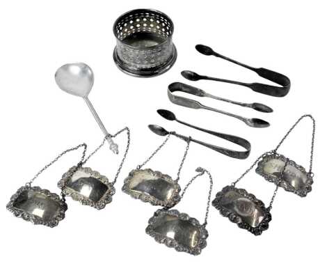 A group of assorted silver plated wares, comprising four decanter labels, three pairs of sugar nips, a salt cellar, and a hammered spoon.