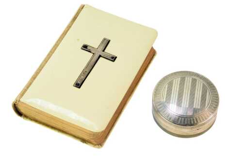 A George V silver pill box, of circular form with engine-turned decoration, Chester 1920, and an ivorine and silver mounted cross Common Prayer book. (2)