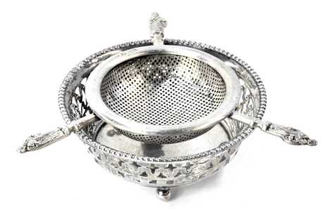 A Victorian silver tea strainer, with three apostle handles, maker R&B, Sheffield 1896, 1.49oz, and a pierced bonbon dish, white metal, stamped sterling, 0.85oz. (2)