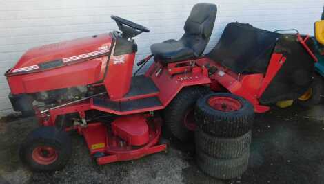 A Westwood T1600 petrol ride on lawn mower, in red, with spare wheels.