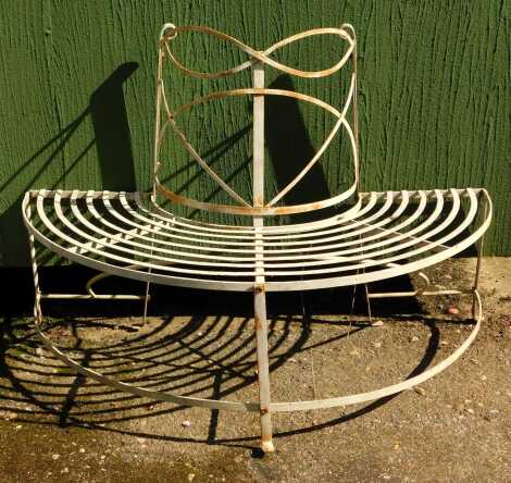 A cast metal garden half-moon tree seat, painted in cream.