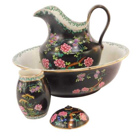 A Cetem ware pottery part wash set, decorated with flowers against a black ground comprising wash jug, 27cm high, bowl, vase, and lid to a powder pot.