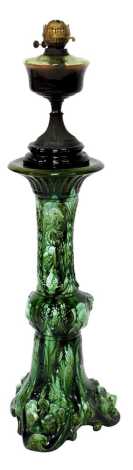 A 20thC green mottled glazed jardiniere stand, relief decorated with scrolls, busts and stylised lion masks, 73cm high, (AF), together with a Victorian oil lamp base, with green glass central reservoir, cast metal base, on a socle, lacking shade and chimn