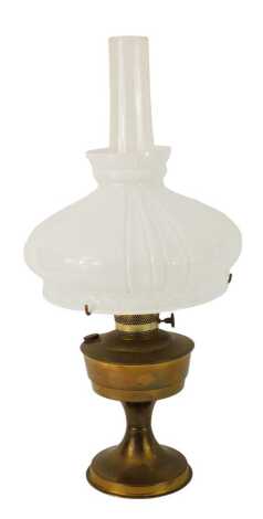 A 20thC oil lamp, with milk glass shade, chimney, with a brass central reservoir, on brass circular foot, 62cm high overall.