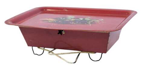 A mid century Worcester ware tin bed table, the rectangular hinged tray top decorated with four horses against a red ground, enclosing a cream enamel recess, on folding leg supports, label to underside, 56cm wide.