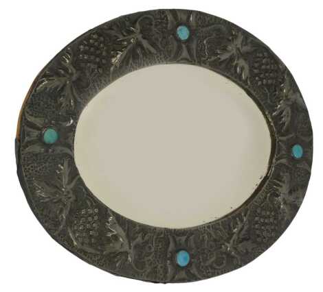 An Arts & Crafts embossed pewter wall mirror, of oval form, decorated with grapes and leaves, with turquoise enamel roundels, 39cm x 49cm.