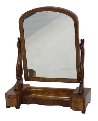 A Victorian flame mahogany swing frame mirror, of arched form, on scrolling pierced supports, the inverted break front base with a hinged compartment enclosing a vacant interior, flanked by two narrow drawers, on scroll feet, 76cm high, 68cm wide, 32cm de