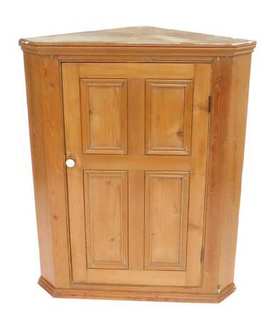 A Victorian pine corner cabinet, the top with a moulded cornice above a four panelled door enclosing three shelves, on a moulded base, 112cm high, 87cm wide, 53cm deep.