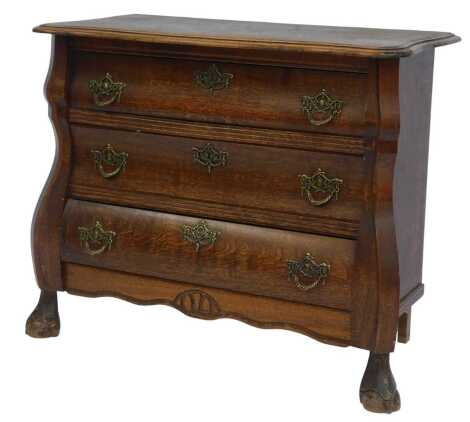 A 20thC oak bombe commode, the top with moulded edge above three drawers, on ball and claw feet, 63cm high, 70cm wide, 34cm deep.