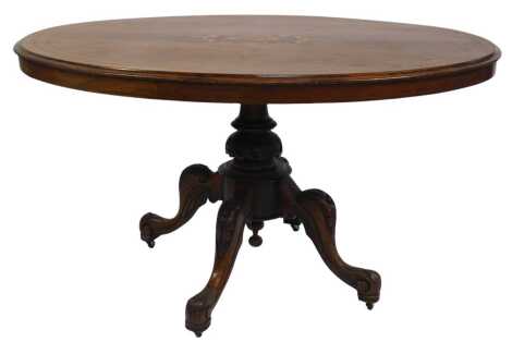 A Victorian oak and marquetry breakfast table, the oval top with marquetry inlay, on a turned and carved column, on four carved cabriole legs and pad feet, on castors, 70cm high, the top 93cm x 130cm.