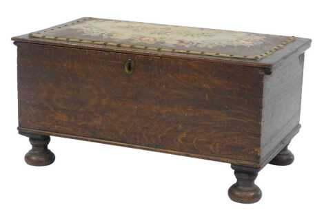 An early 20thC oak chest, the rectangular top inlaid with a floral tapestry panel enclosing vacant interior, on compressed turned feet, 37cm high, 73cm wide, 41.5cm deep.